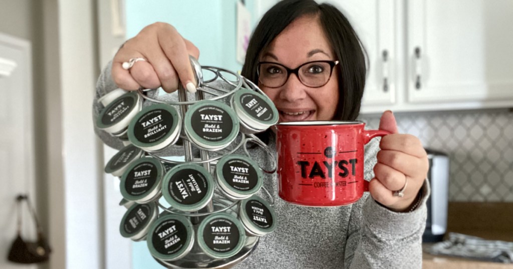 woman holding tayst coffee pods and a red tayst coffee mug