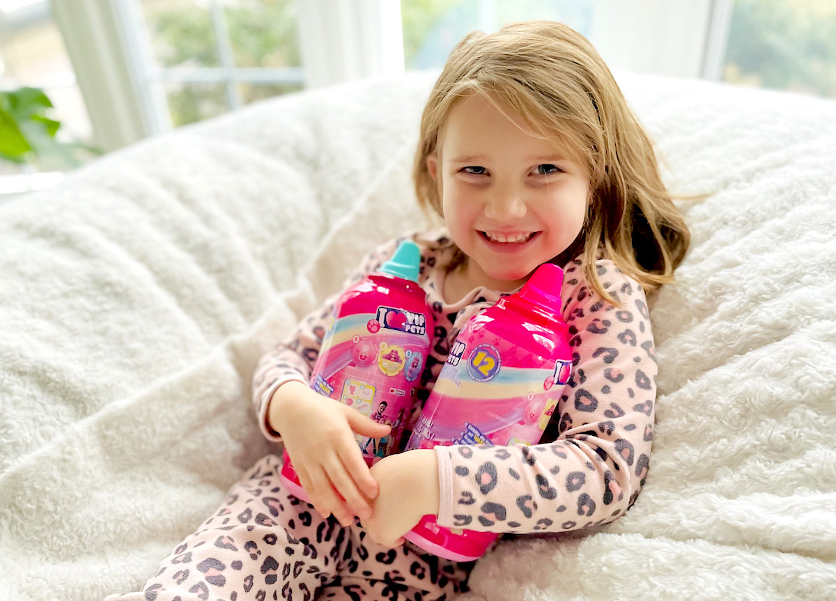 girl holding two vip pet doll surprise toys in hands smiling