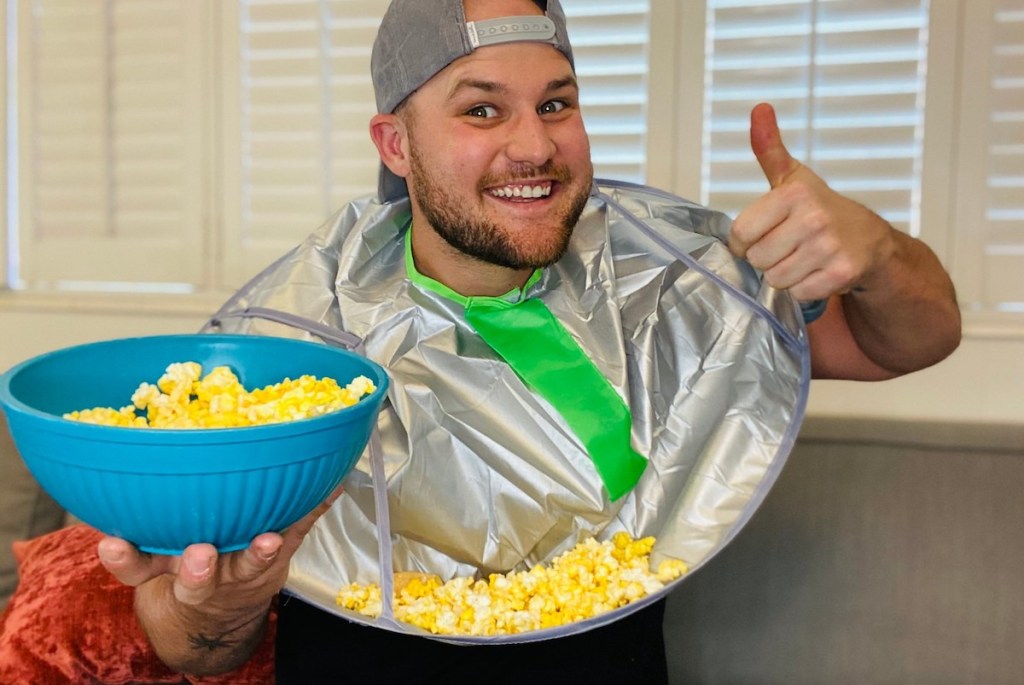 man giving thumbs up holding bowl of popcorn and wearing an adult bib