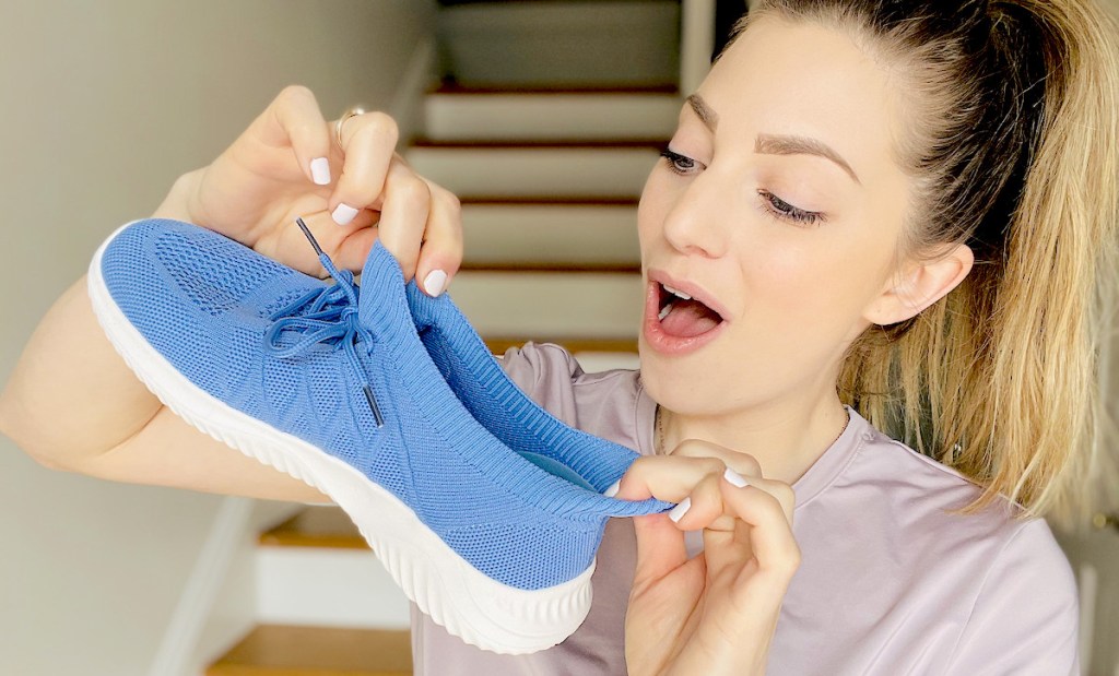 woman holding blue walking shoe and stretching it out