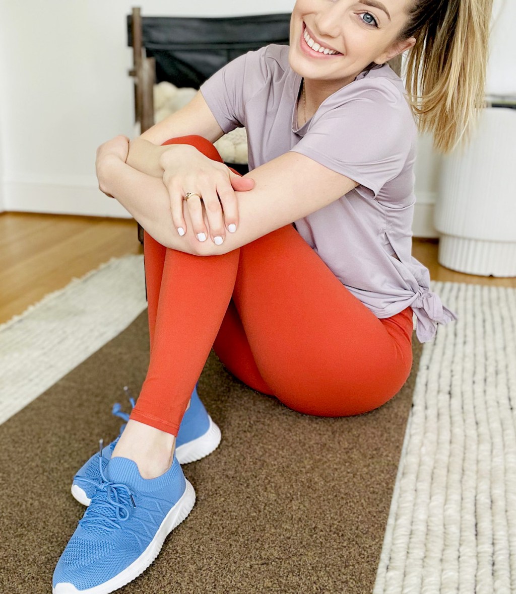 woman wearing blue sneakers and red leggings smiling 