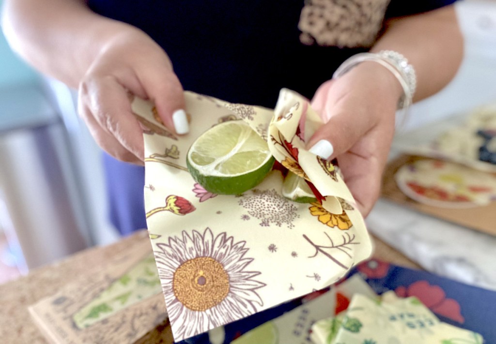 hands holding floral beeswax wraps with half but lime inside