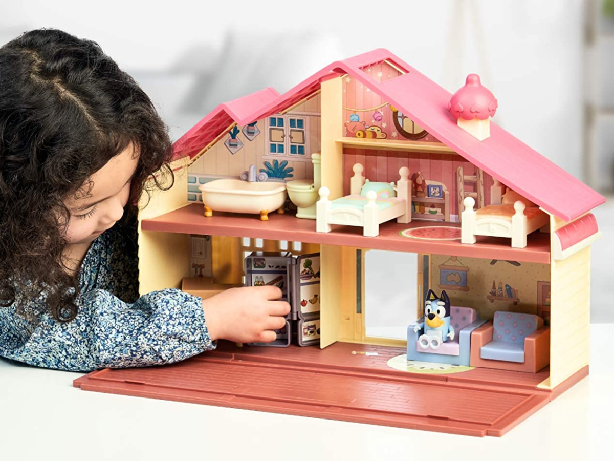girl playing with a bluey doll house