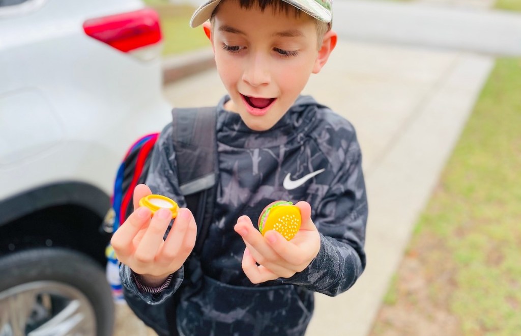 boy holding miniature burger lip balm outside - April fools pranks