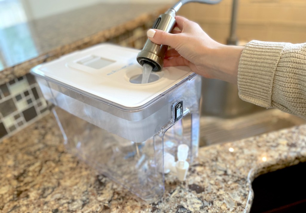 hand holding water faucet over hole in water filter