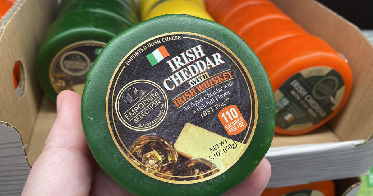 hand holding an irish cheddar with whiskey in front of a store display