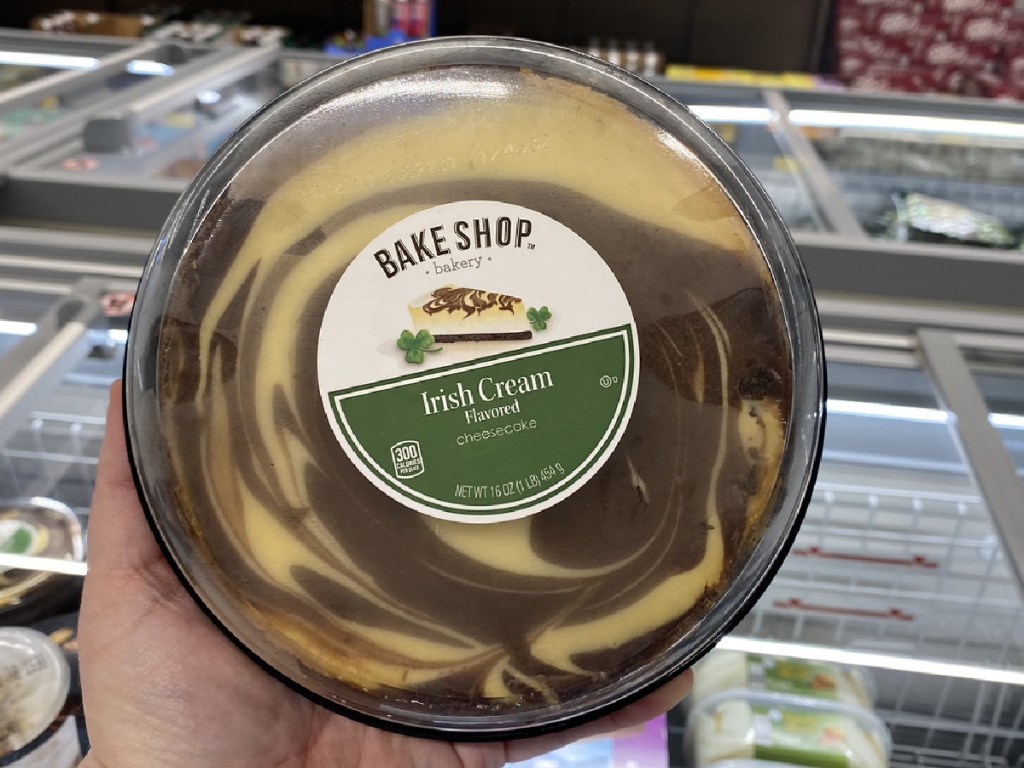 hand holding up cheesecake by store freezer