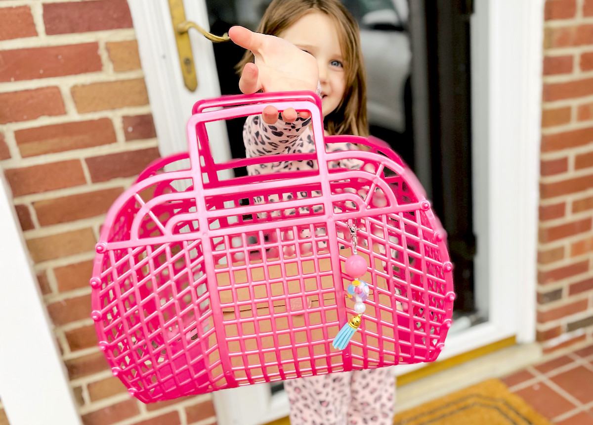 girl holding up a pink jelly bag in front of front door