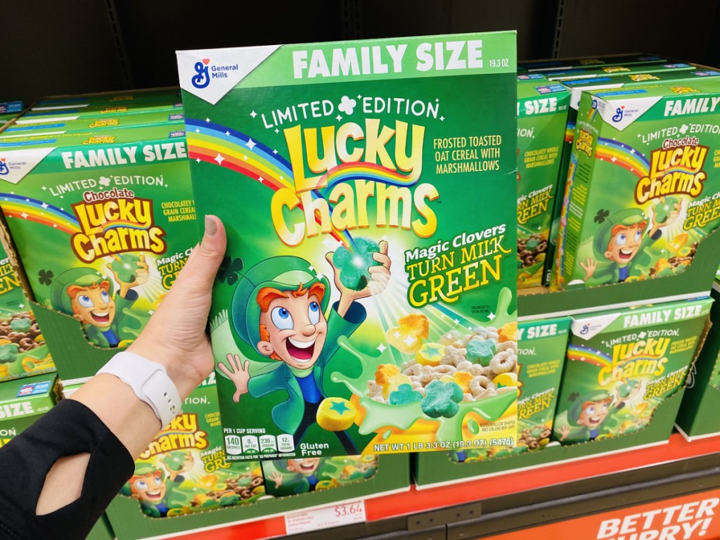 hand holding box of green colored cereal in store