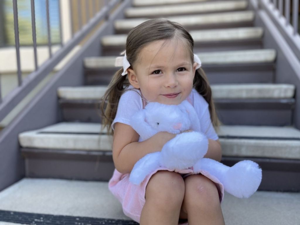 girl sitting on steps holding white bunny