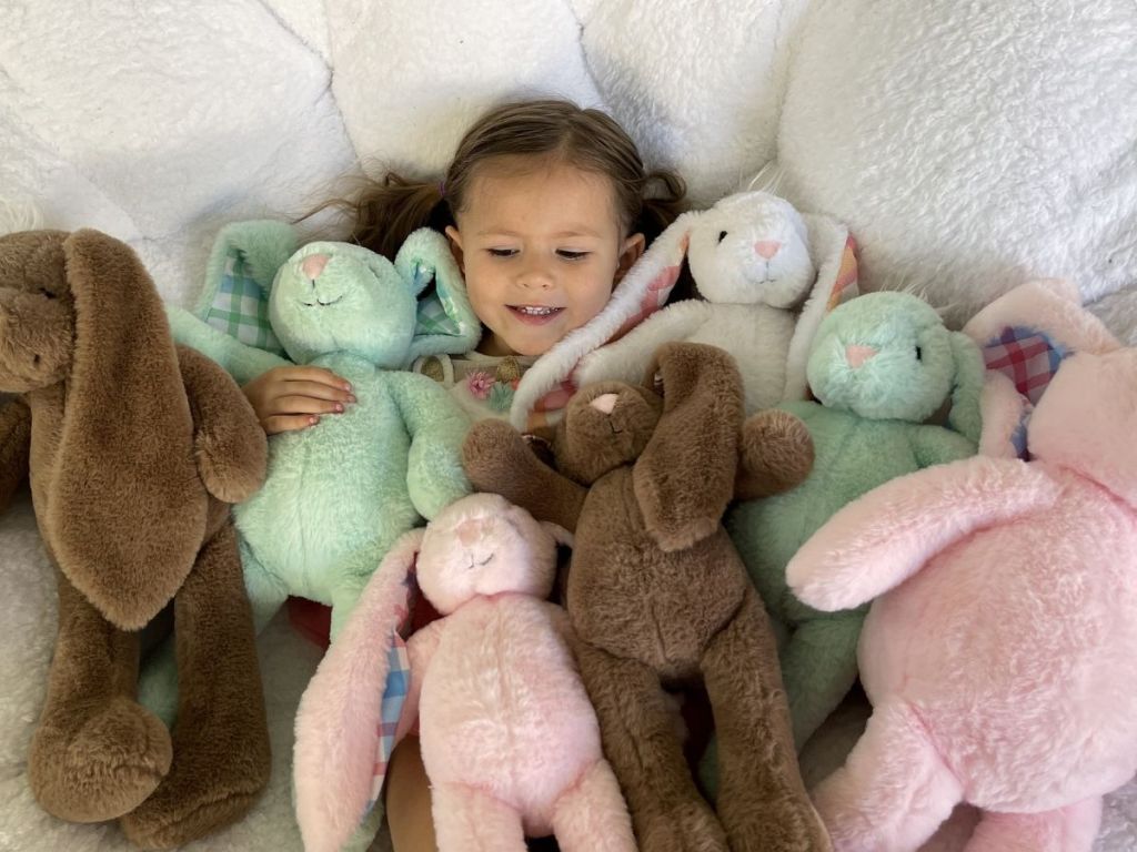 little girl in chair with lots of plush bunnies