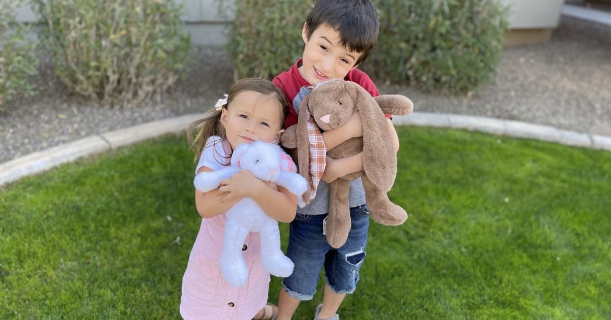girl and boy hugging plush bunnies outside