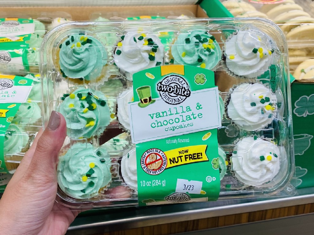 hand holding package with small sized cupcakes by store display
