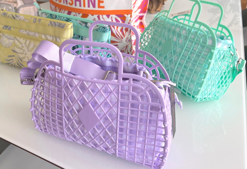 close up of purple jelly tote on white table with various styles of bags