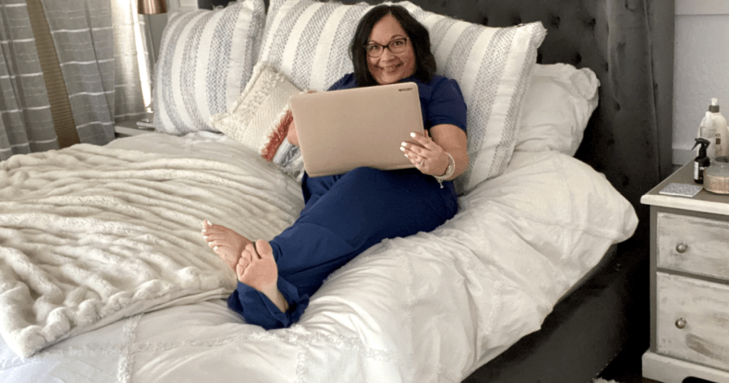 woman wearing pajamas in bed on laptop