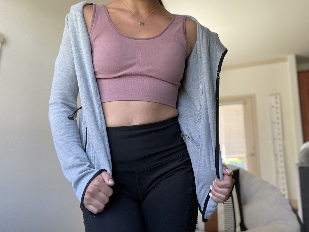 woman wearing gray zip up sweatshirt and mauve sports bra