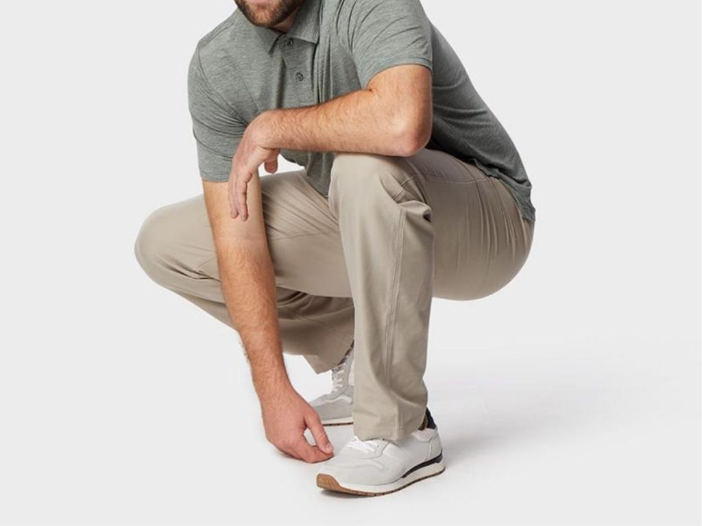man wearing green polo and tan pants crouching