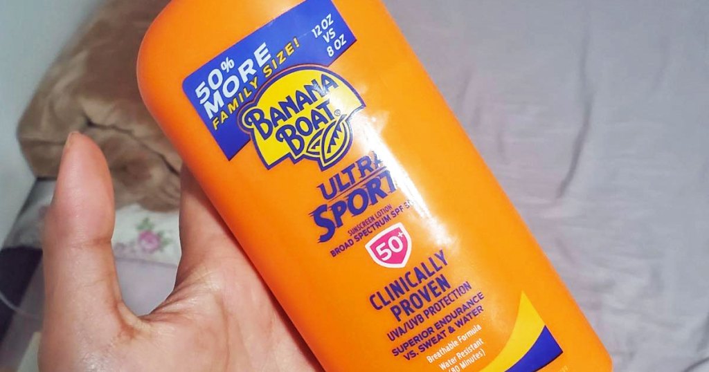 person holding orange bottle of banana boat sunscreen