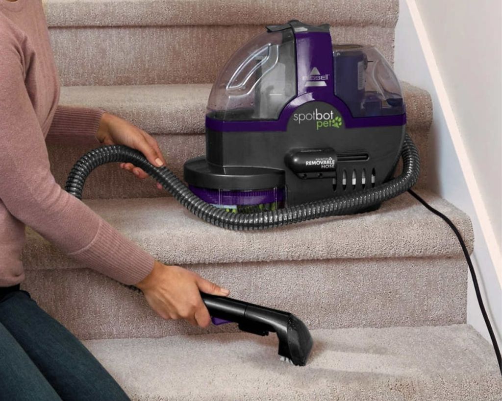 person using Bissell SpotBot Pet Deep Cleaner on stairs