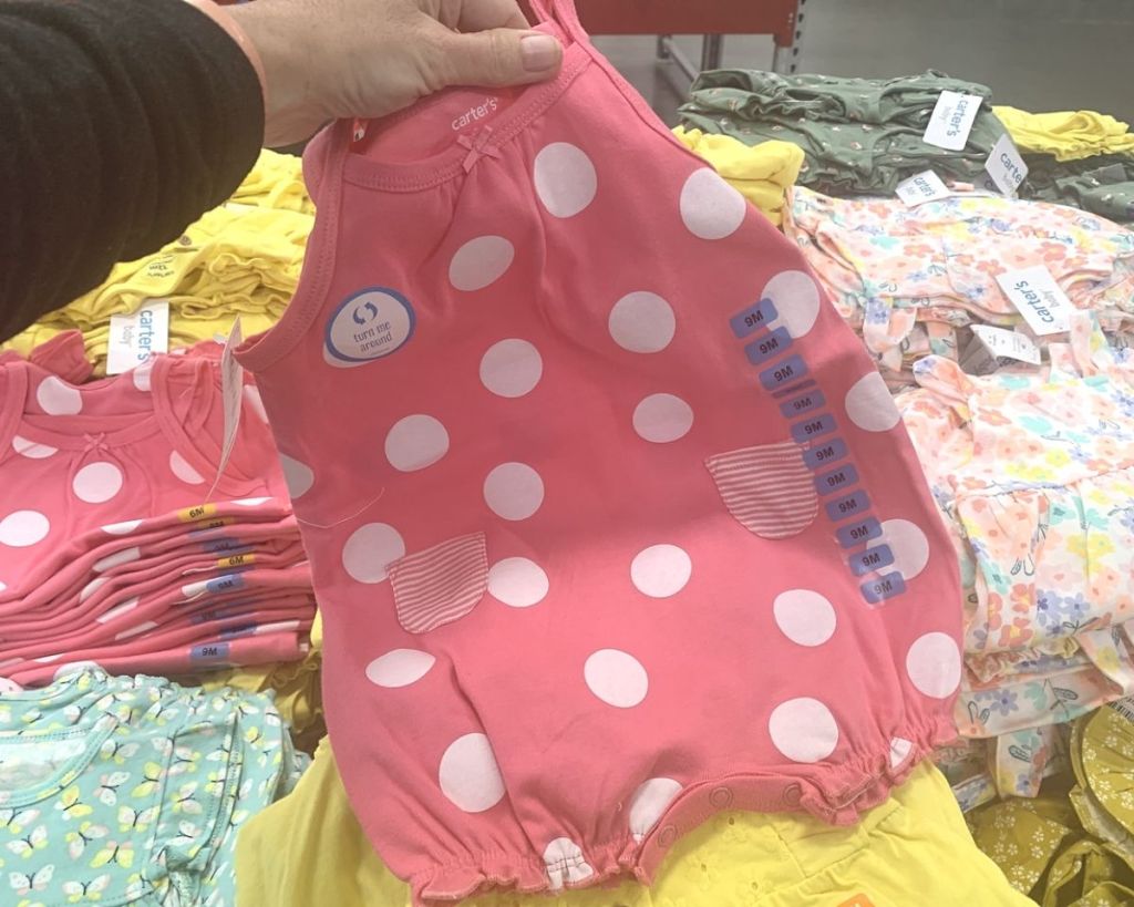 hand holding Carter's Pink and White Polka Dot Romper
