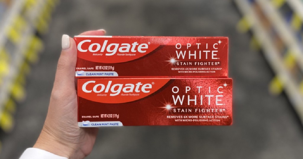 hand holding two red boxes of toothpaste
