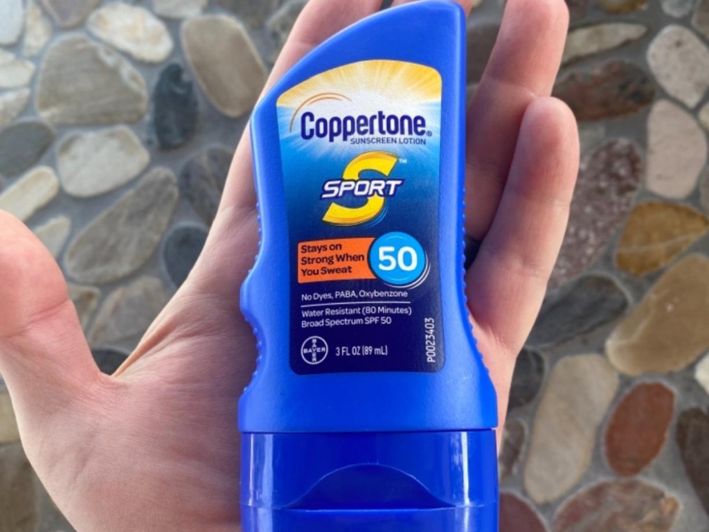 hand holding travel size bottle of sunscreen