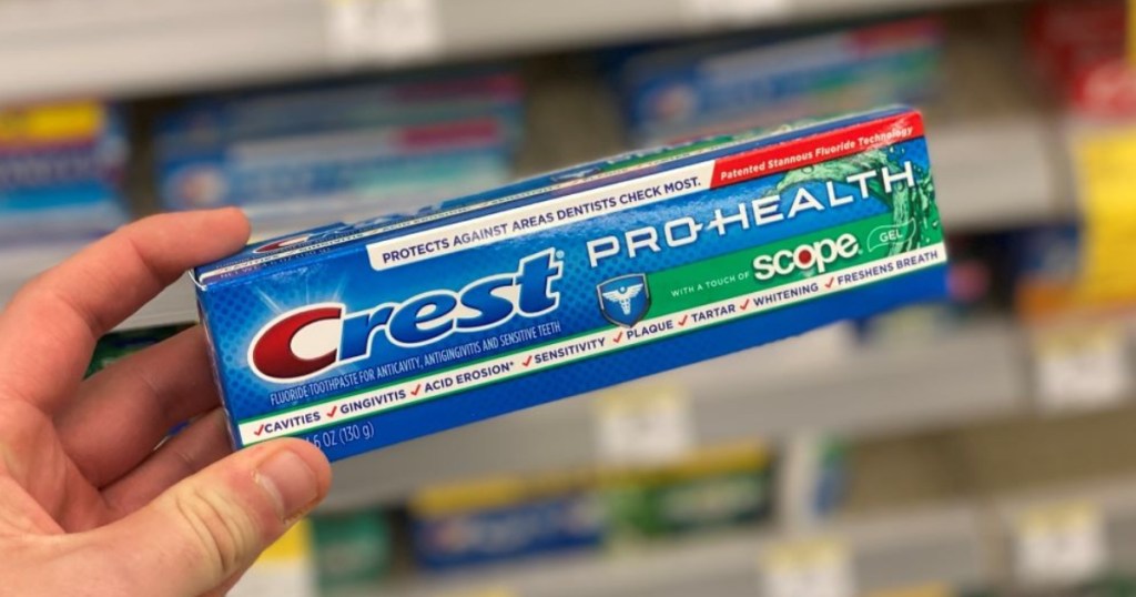 holding Crest toothpaste in box