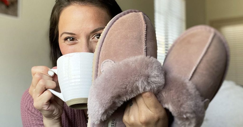 woman holding up a cup of coffee and pair of dusty rose colored slippers