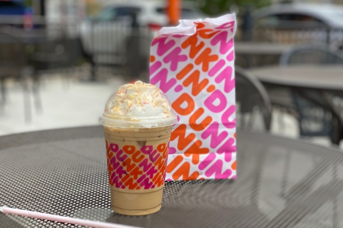 Dunkin' Butter Pecan Sundae Signature Iced Latte with a dunkin bag on an outdoor table