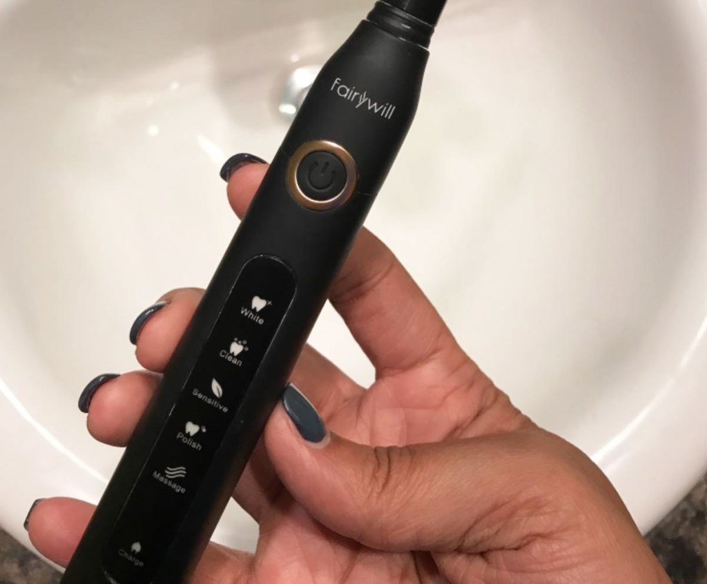 hand holding black electric toothbrush