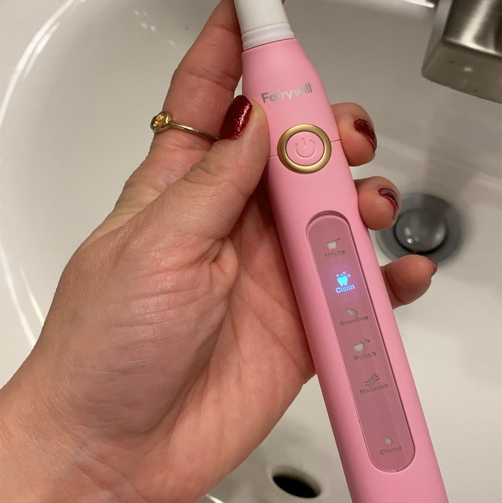 hand holding pink electric toothbrush