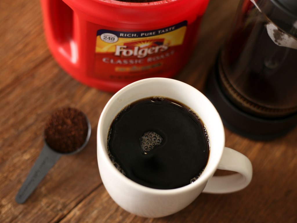 cup of coffee in front of canister of folgers coffee