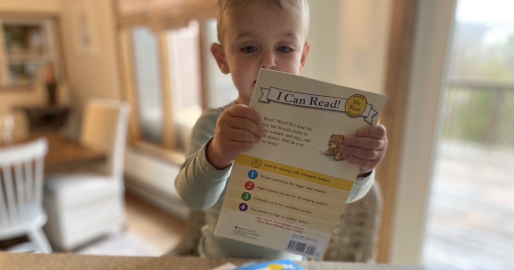 little boy holding up an I Can Read Book