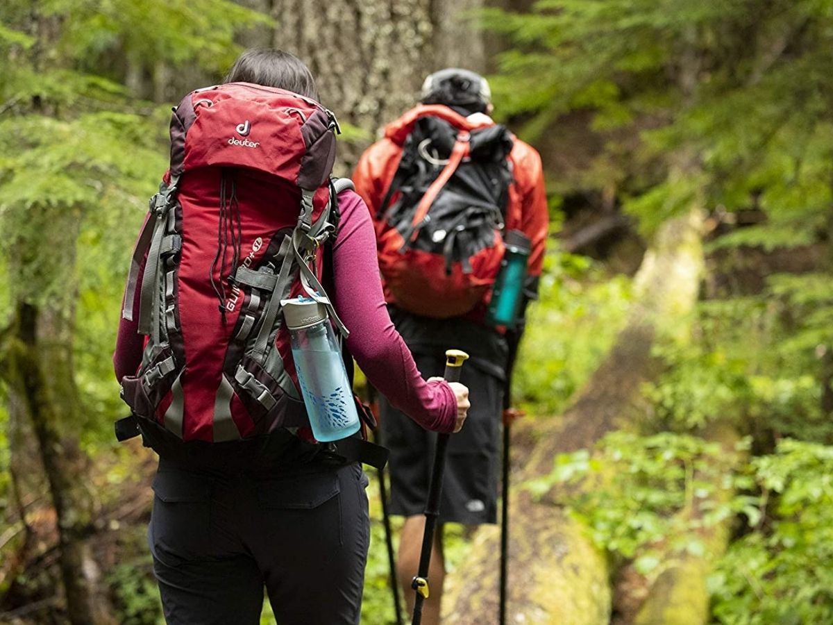 woman and man hiking with lifestraw water bottles secured to their backpacks