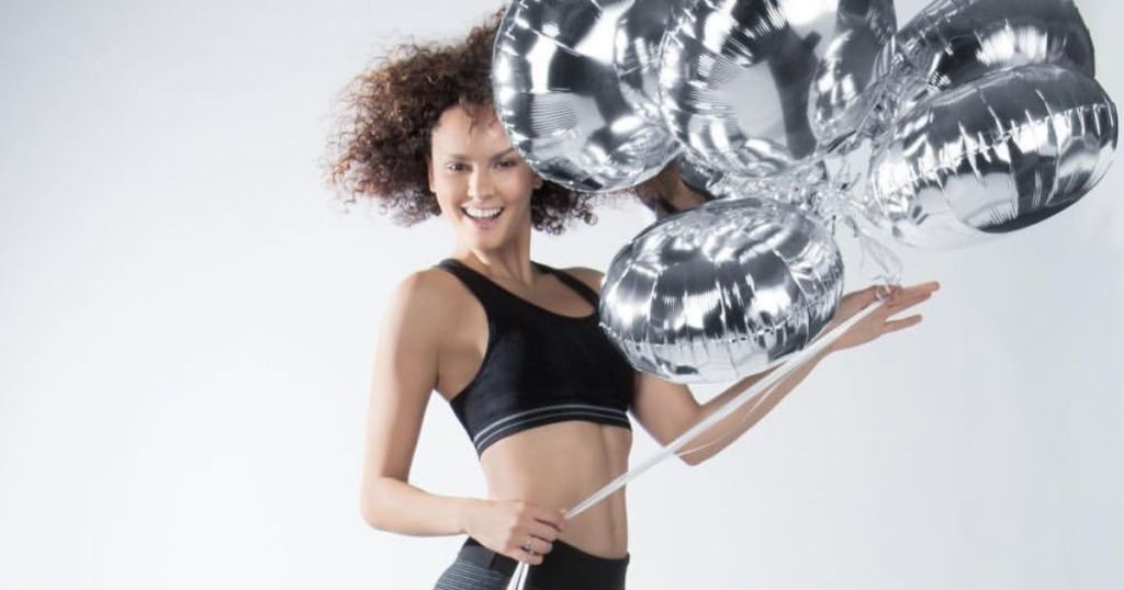 woman in a sports bra holding a bunch of balloons