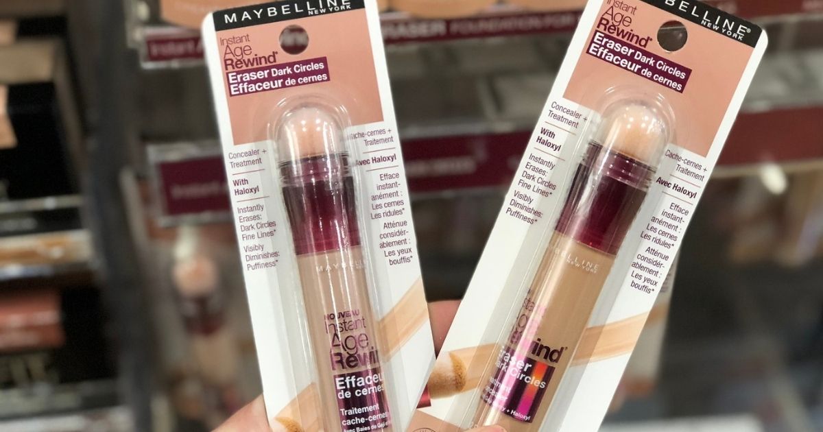 hand holding two Maybelline age rewind Concealers in front of a store shelf