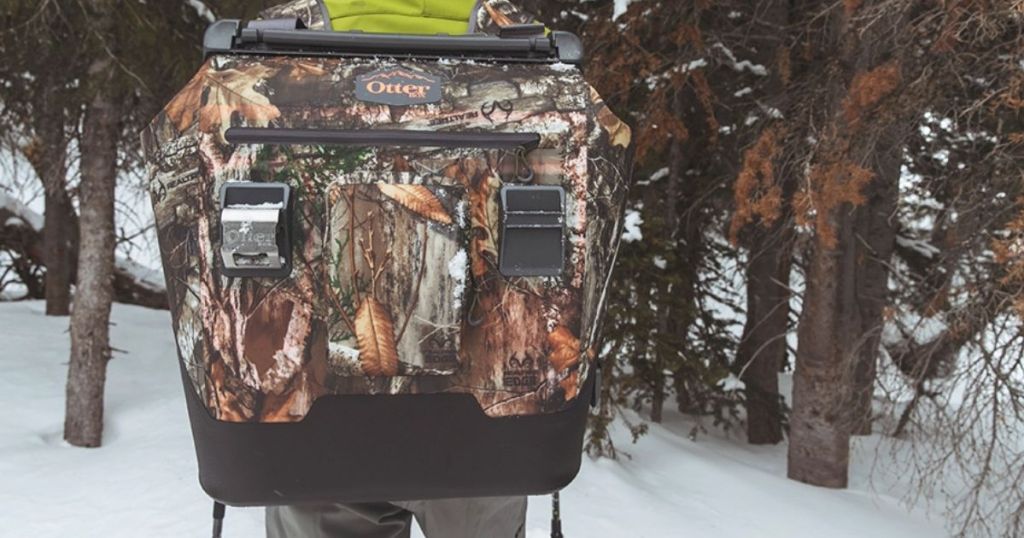man carrying camo Otterbox cooler on his back