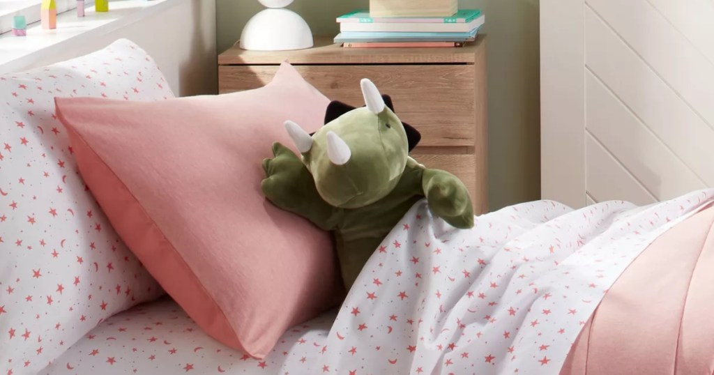 green dinosaur pillow in a child's bed