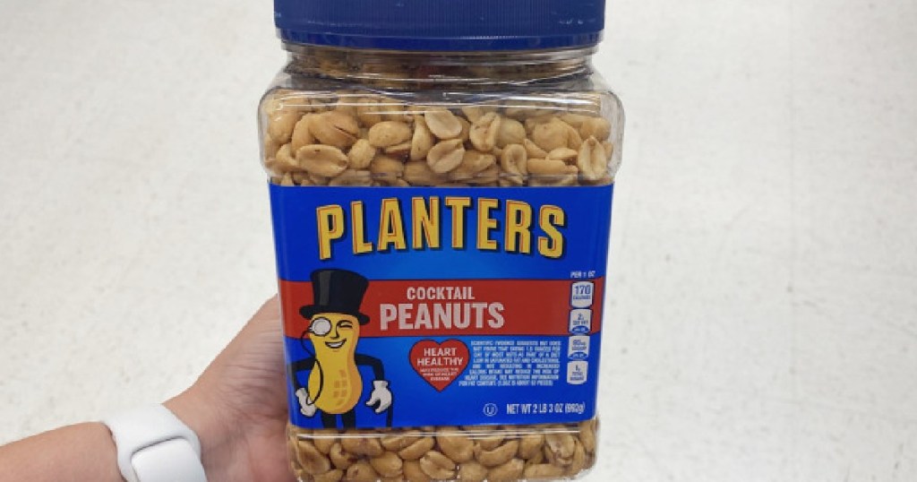 hand holding a large canister of planters peanuts