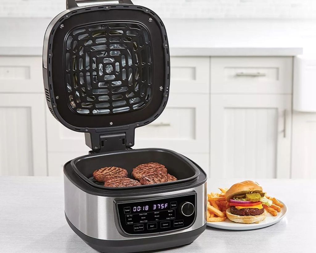 PowerXL Grill Air Fryer Combo with burgers inside and a plate of food