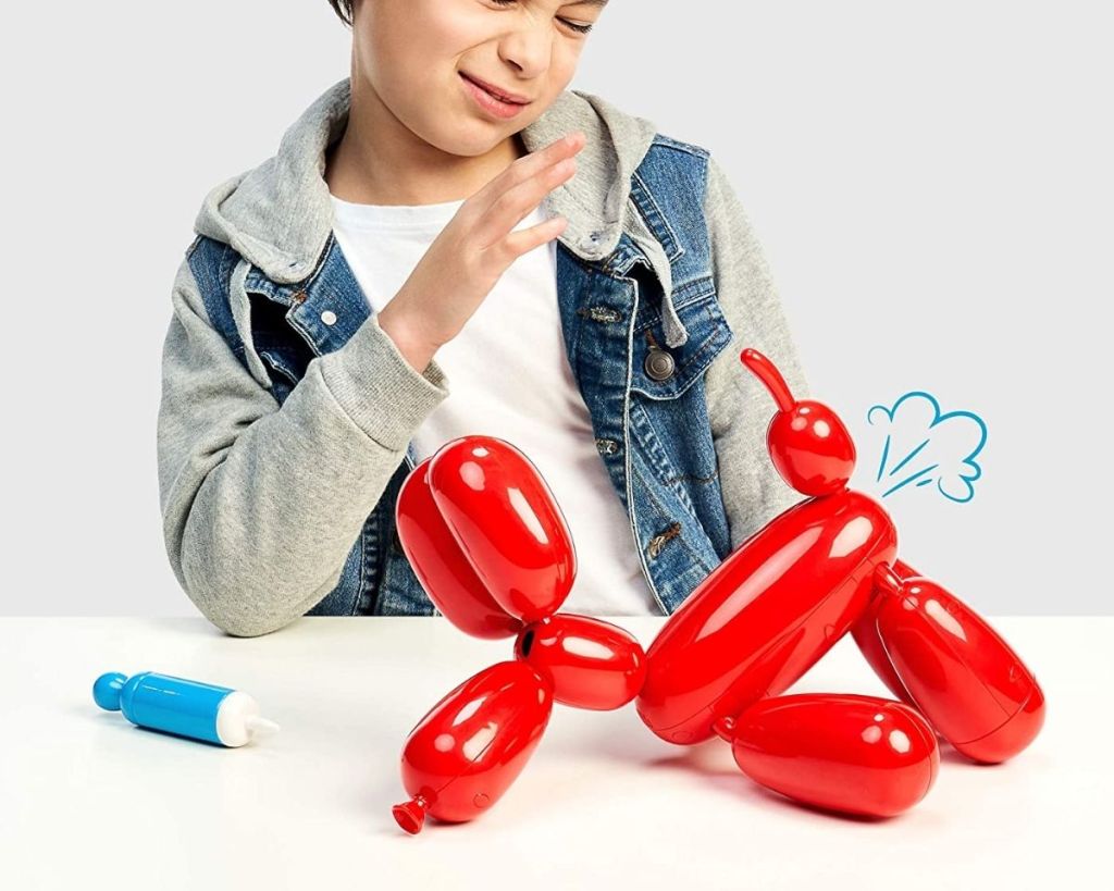 boy playing with Squeakee The Balloon Dog who is tooting