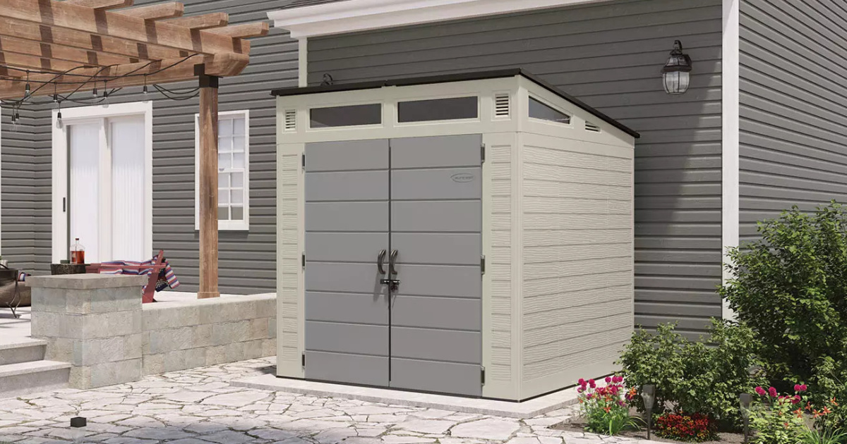 suncast storage shed next to a garage wall and a pergola