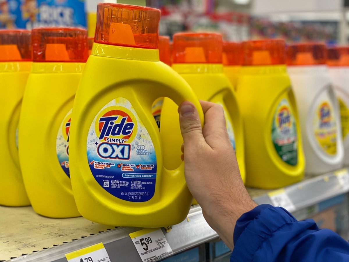 hand pulling out a bottle of Tide Simply Oxi