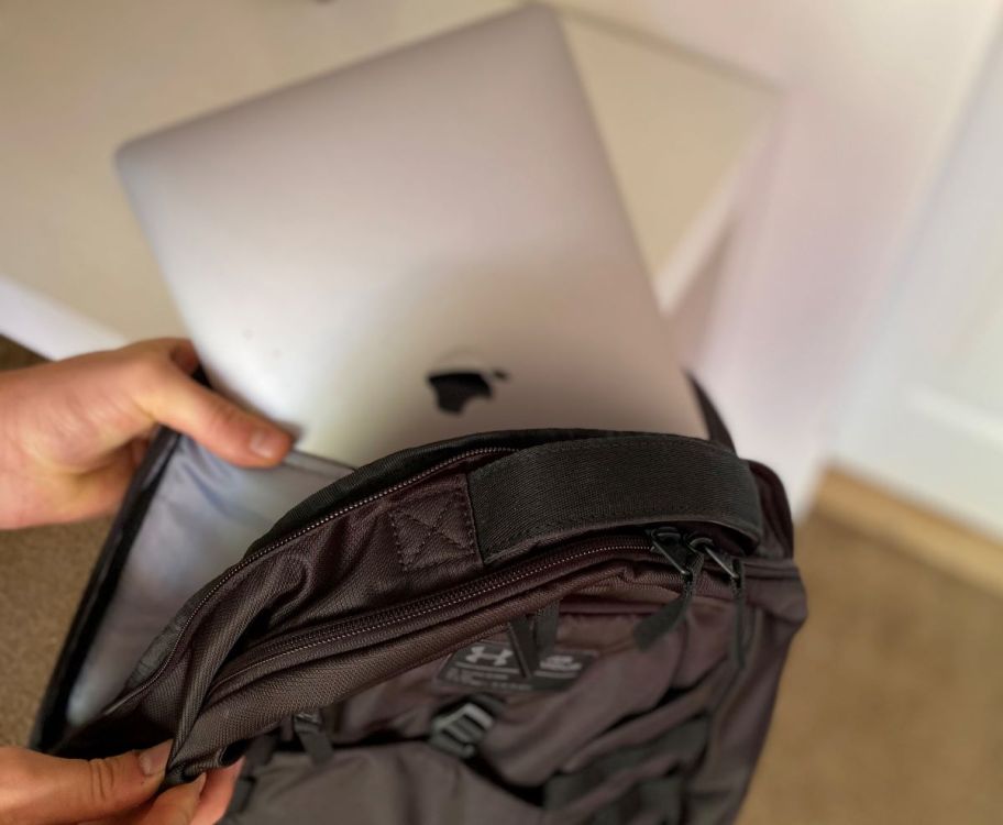 hand putting a laptop into a backpack