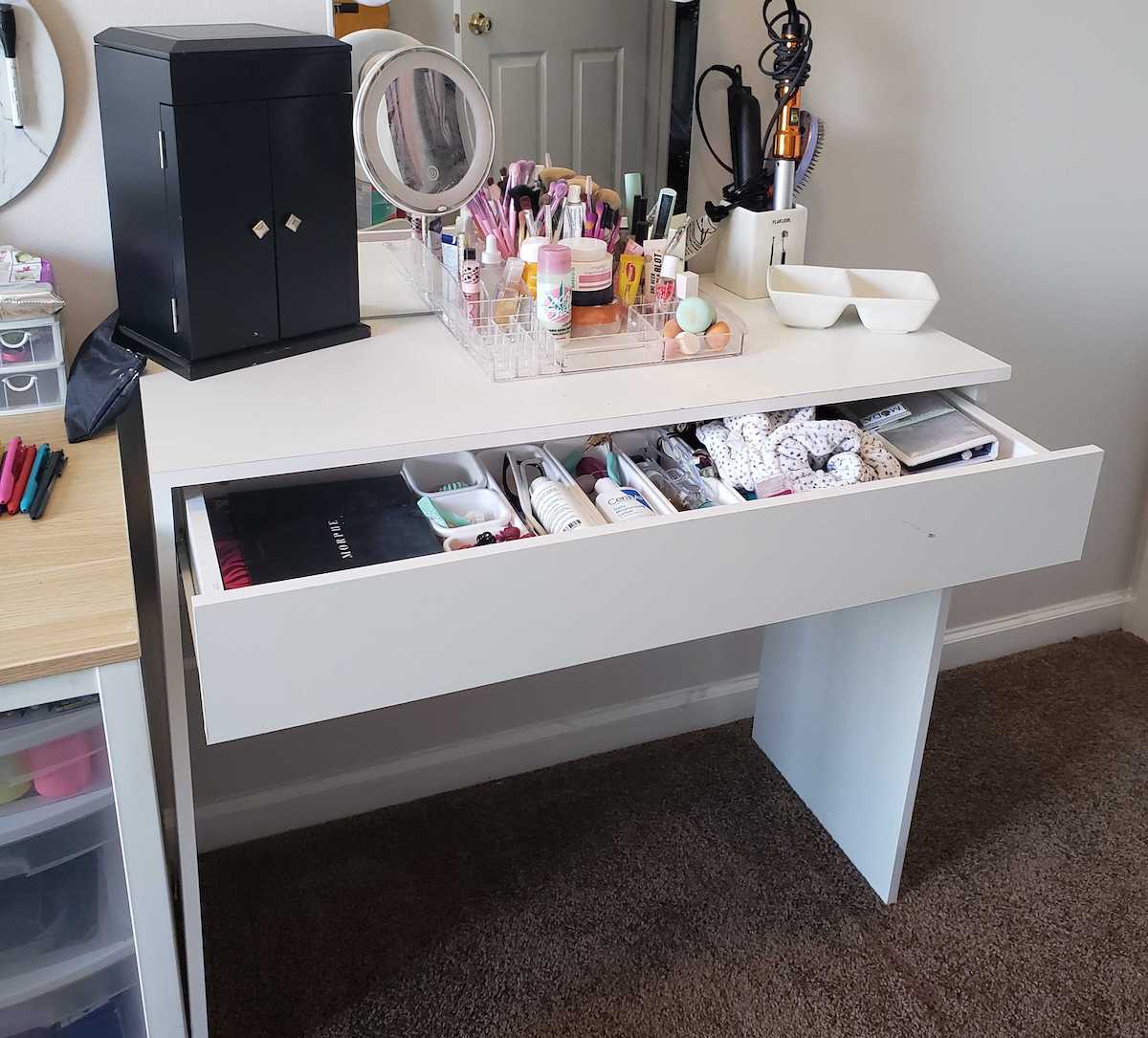 white vanity desk with drawer open and full of cosmetics
