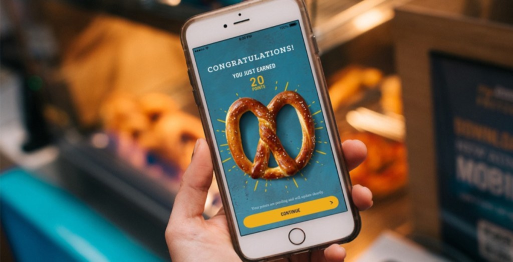 holding a phone open to the Auntie Anne's app