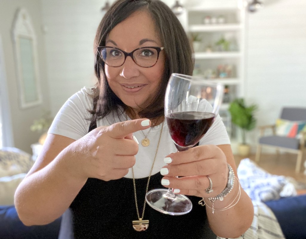 woman holding and pointing to a glass of red wine