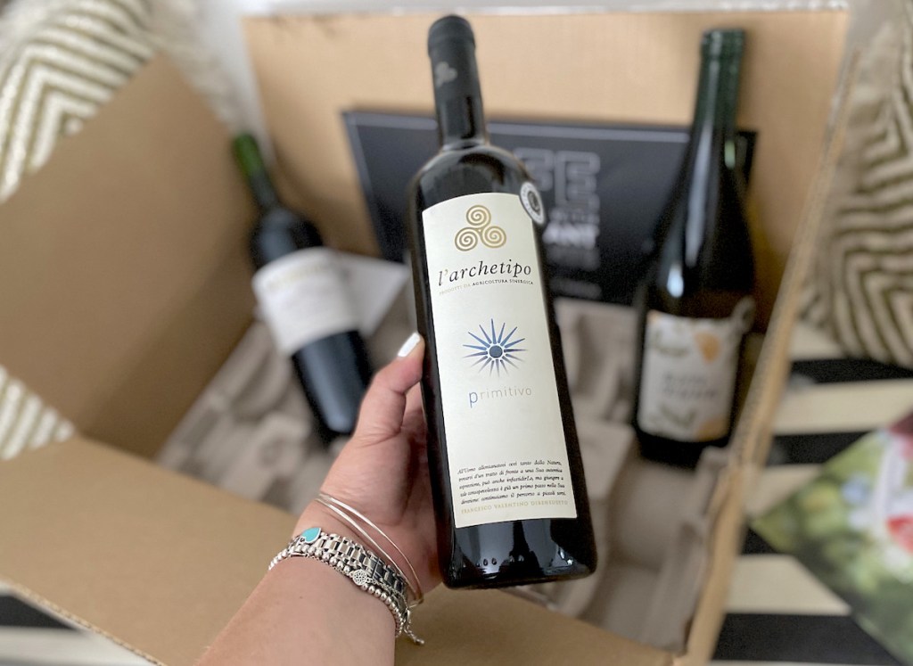 hand holding a bottle of wine from delivery box