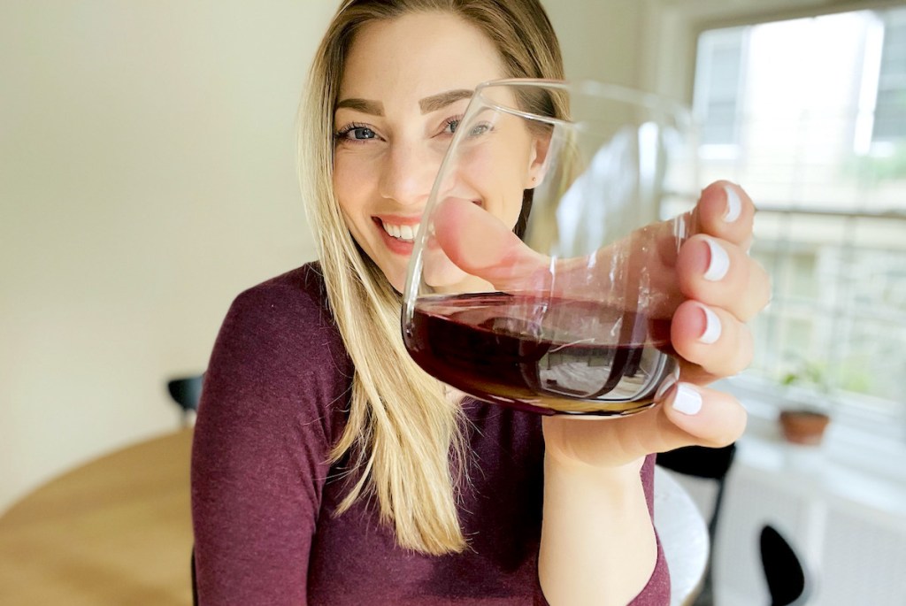 woman holding up a glass of red wine smiling