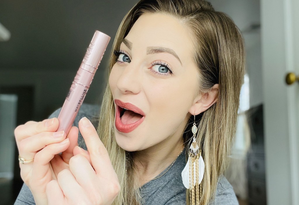 woman holding up maybelline sky high mascara looking surprised